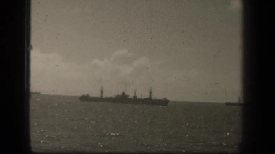 Distant naval vessel at sea in reported Leyte Gulf footage, seen through soft, grainy 1940s 8mm framing.