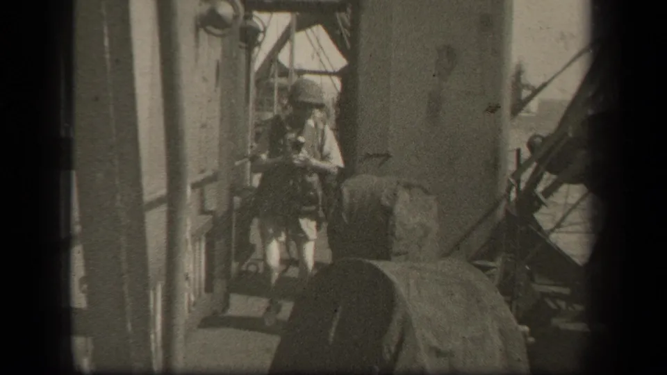 Helmeted sailor on a battleship deck in reported 1944 Leyte Gulf footage, moving near equipment and deck structures.