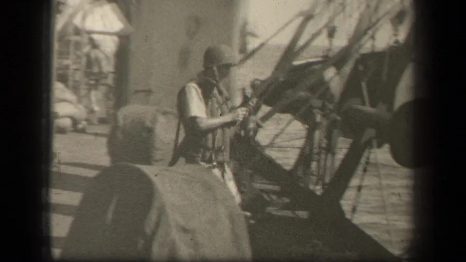 A sailor in helmet and life vest appears beside large shipboard equipment in reported Leyte Gulf naval footage.