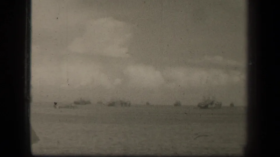 1944 Leyte Gulf footage showing a hazy line of distant naval ships across open water under heavy cloud cover.