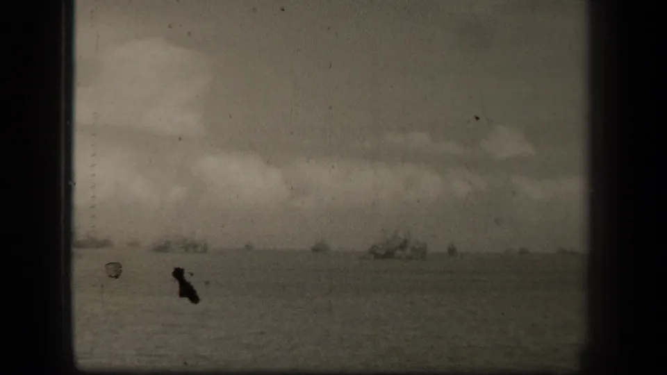 A grainy 8mm view of open water in Leyte Gulf, with distant ships beneath a layered cloud bank.