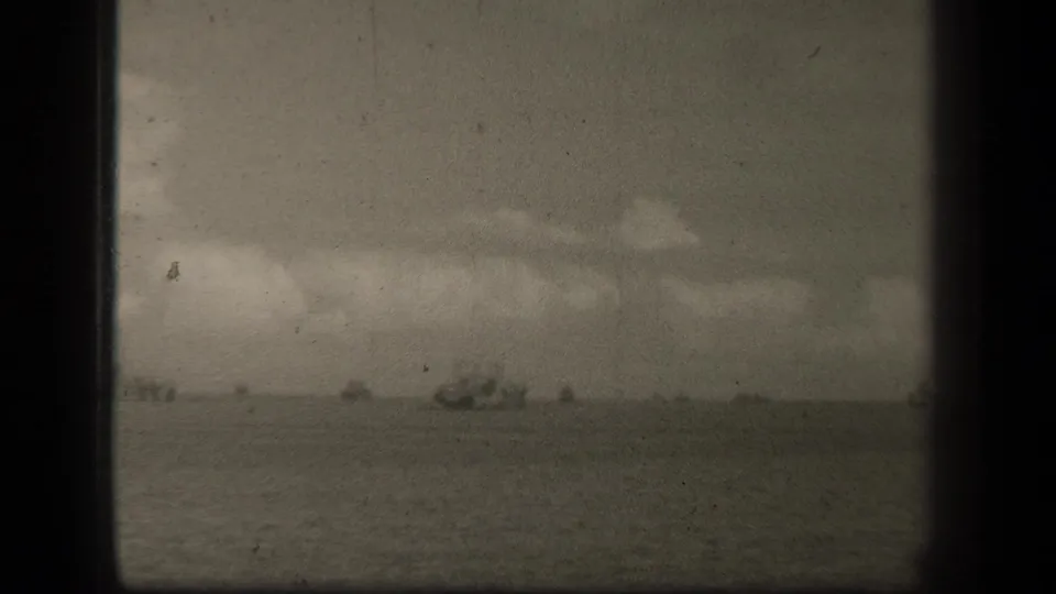 1944 8mm view of Leyte Gulf water with small ship silhouettes on the horizon beneath cloud cover.