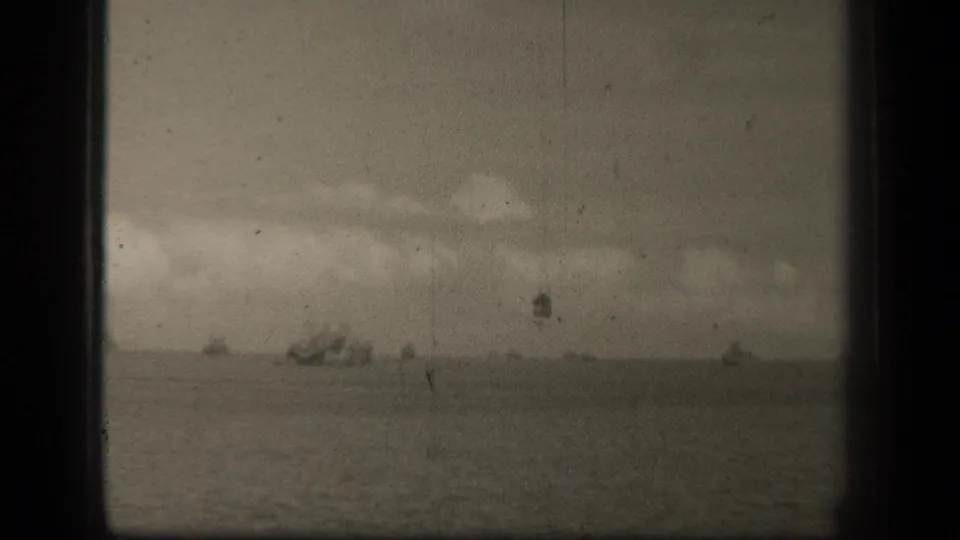 Grainy 8mm frame from Leyte Gulf showing open water, cloud cover, and far-off ship shapes near the horizon.