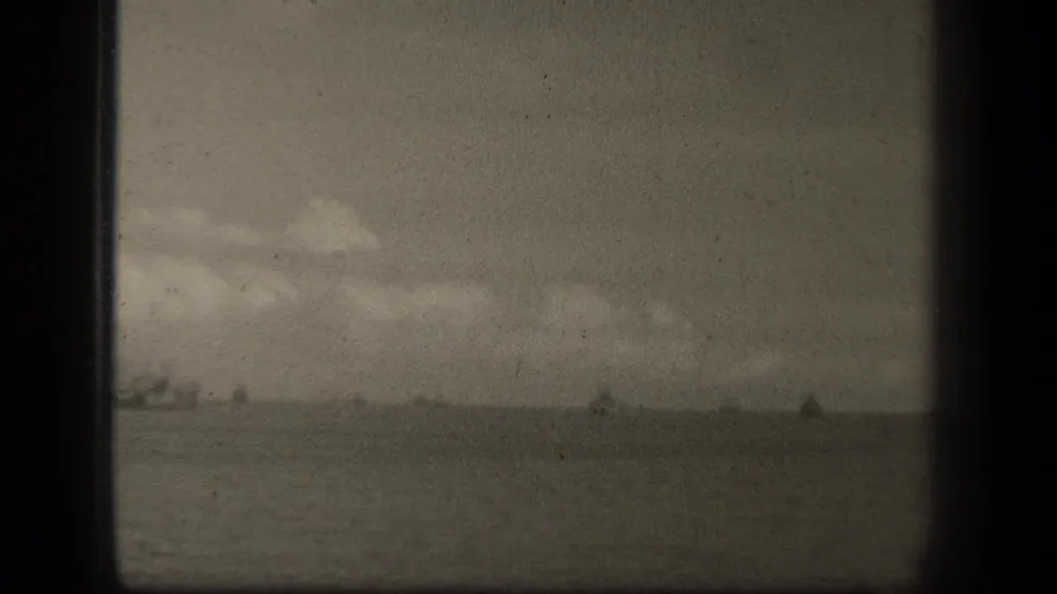 Leyte Gulf appears as a broad 1944 seascape, with small distant vessels under a cloudy sky on worn 8mm film.