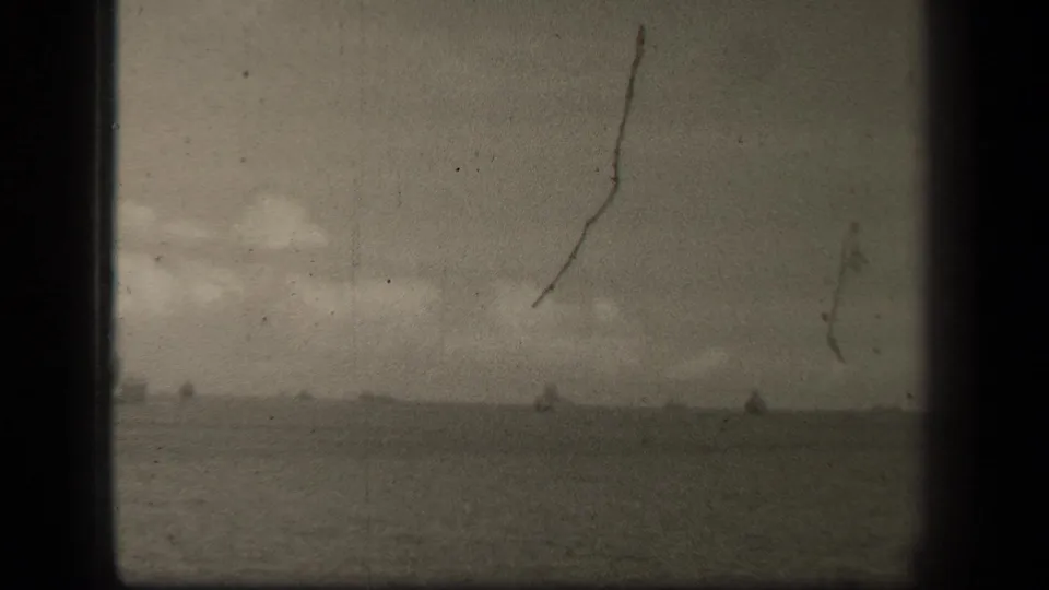 1944 Leyte Gulf footage showing faint naval vessels on the horizon, with heavy grain, scratches and dark frame edges.