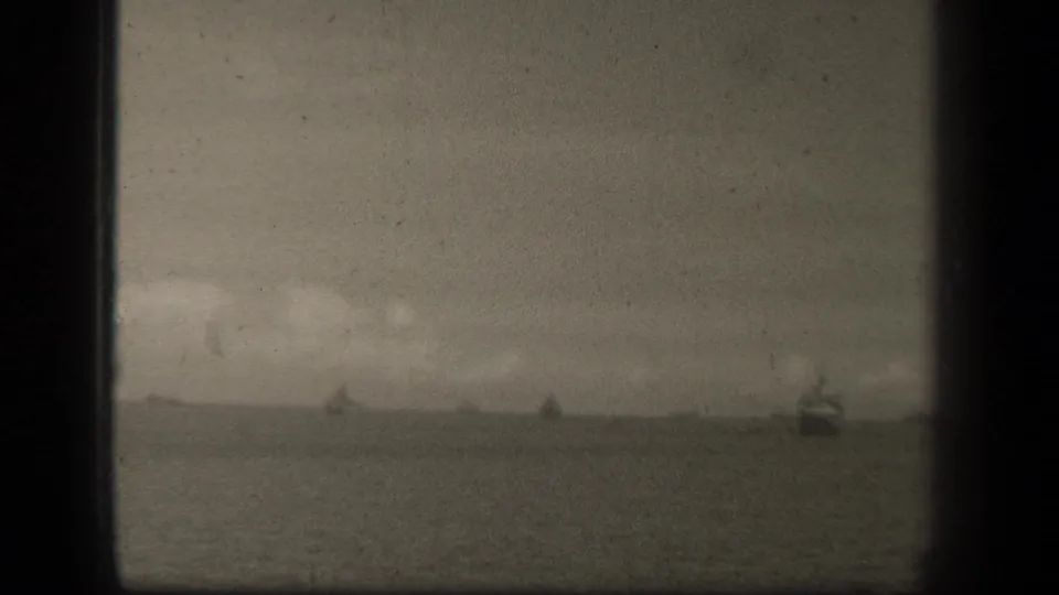 Grainy Leyte Gulf frame with a low horizon, faint ships and a larger dark vessel shape near the right edge.