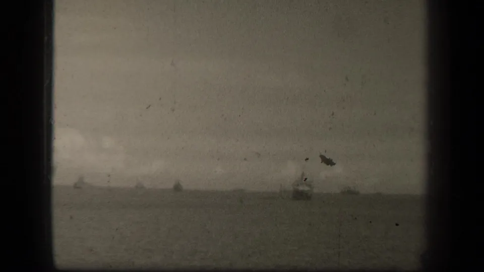 1944 Leyte Gulf 8mm frame showing a hazy water horizon with small distant naval vessels and visible film wear.