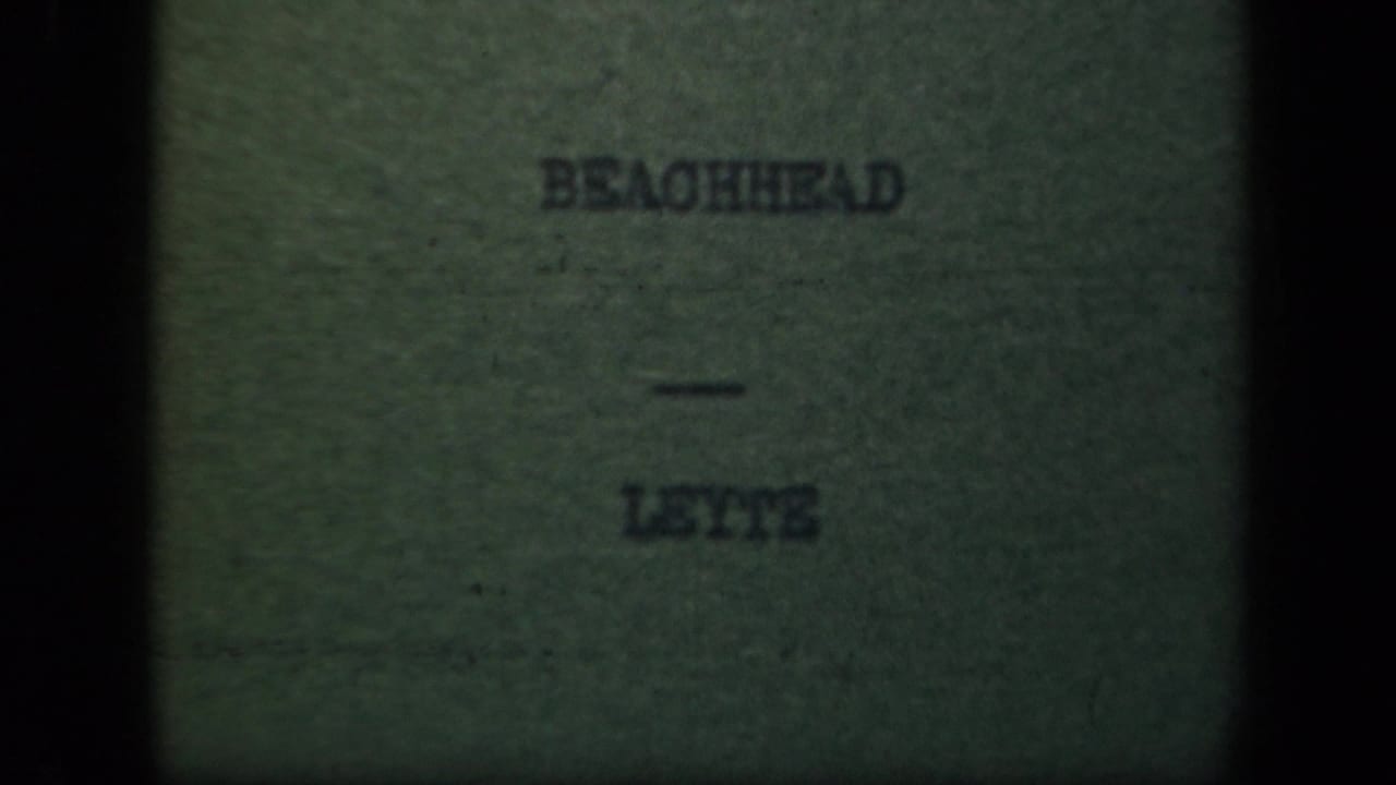 1940s 8mm title card for the Leyte beachhead sequence, with the words BEACHHEAD - LEYTE centered in a darkened frame.