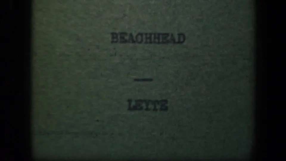 1940s 8mm title card for the Leyte beachhead sequence, with the words BEACHHEAD - LEYTE centered in a darkened frame.