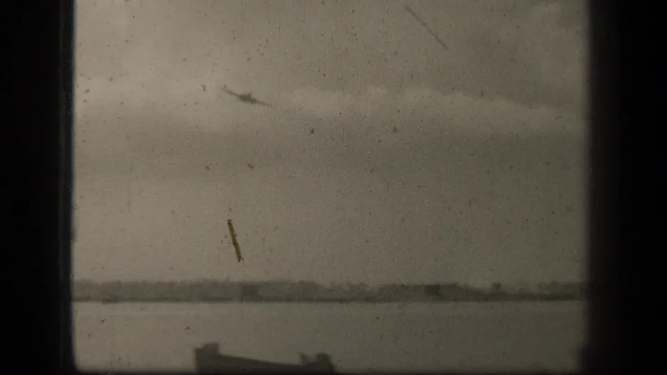 Distant aircraft crosses the overcast Leyte Gulf sky while part of a small boat appears along the bottom edge.