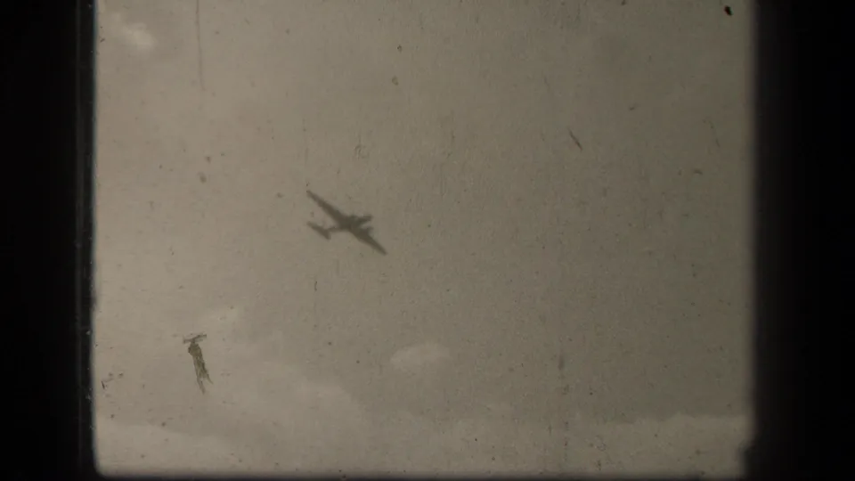 Black-and-white 8mm Leyte Gulf frame showing a small aircraft silhouette over cloudy sky with prominent film wear.
