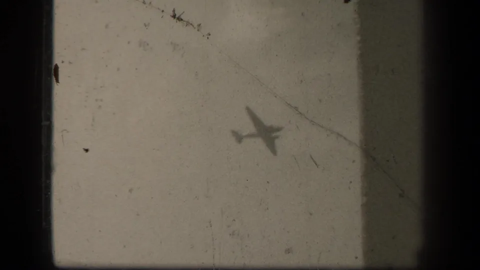 Aircraft silhouette crossing pale cloud cover in the supplied 1944 Leyte Gulf shipboard footage.