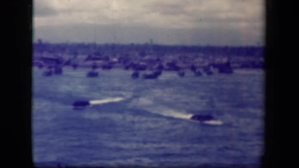 1944 Leyte Gulf view showing two dark craft crossing choppy water, with many distant ships under a cloudy sky.