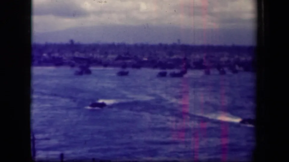 Final Leyte Gulf frame with a dark craft and bright wake at lower right, distant vessels, cloudy sky, and visible film wear.