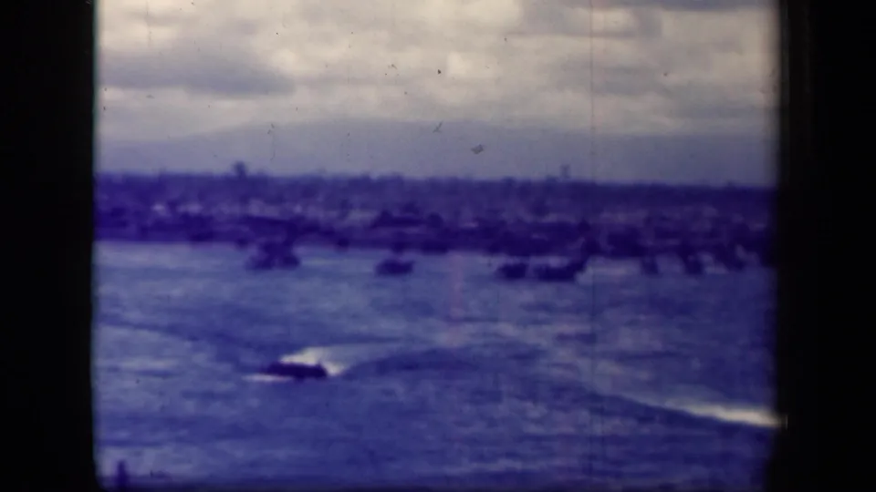 1944 Leyte Gulf 8mm frame with multiple small craft on open water and a low shoreline in the distance.
