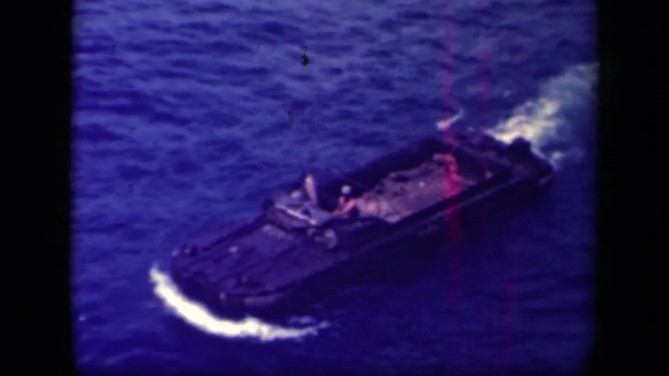 1944 Leyte Gulf 8mm frame showing a tracked amphibious vehicle from above, with a soldier visible aboard as it moves through water.