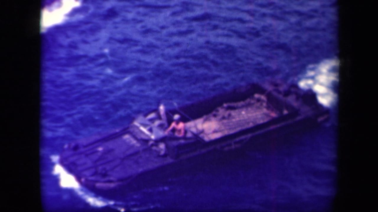 Leyte Gulf 1944 frame of a small military landing craft passing through blue water, with one crew member visible near the middle.