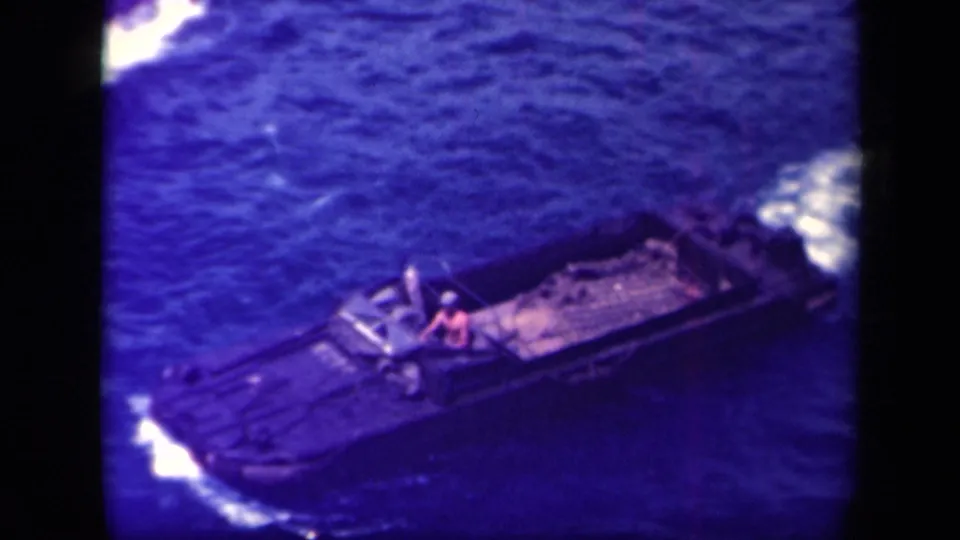 Leyte Gulf 1944 frame of a small military landing craft passing through blue water, with one crew member visible near the middle.