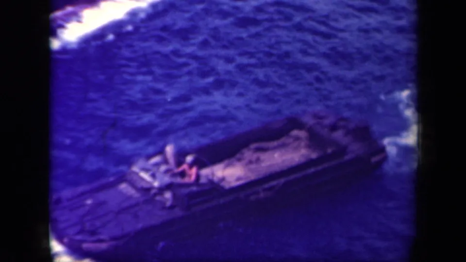 Soft 8mm frame from 1944 Leyte Gulf footage showing a landing craft angled across choppy water with a visible crew figure.