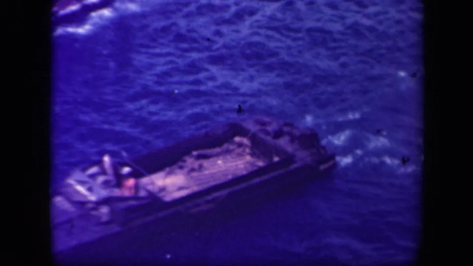 Final 1944 Leyte Gulf frame showing the dark landing craft in choppy water, with a single figure visible and wake around the stern.
