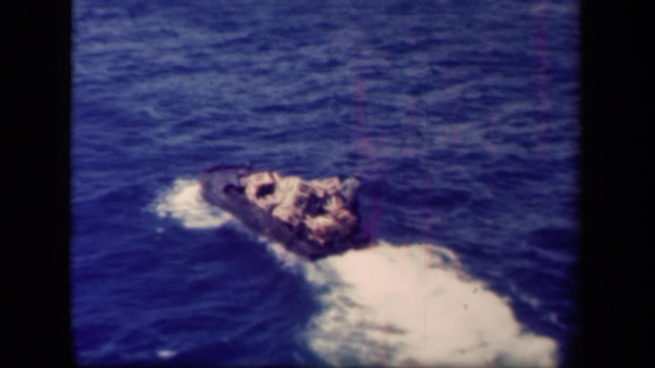 1944 Leyte Gulf 8mm frame showing a small loaded boat crossing deep blue water and leaving a bright wake.