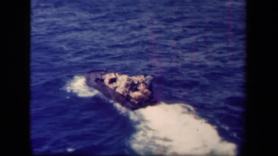 1944 Leyte Gulf 8mm frame showing a small loaded boat crossing deep blue water and leaving a bright wake.