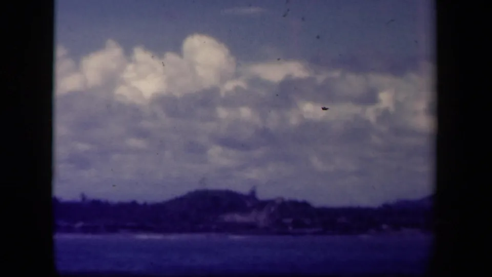 Leyte Gulf frame from 1944 showing clouds, distant coastal land, and dark blue water with visible film dust.