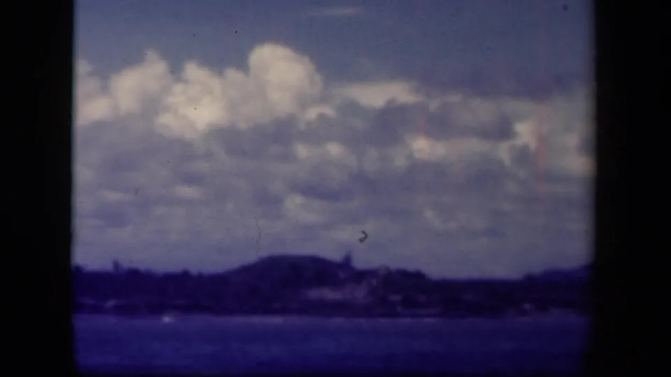 1944 Leyte Gulf 8mm view of a hazy coast and cloud bank across open water, with visible film wear.