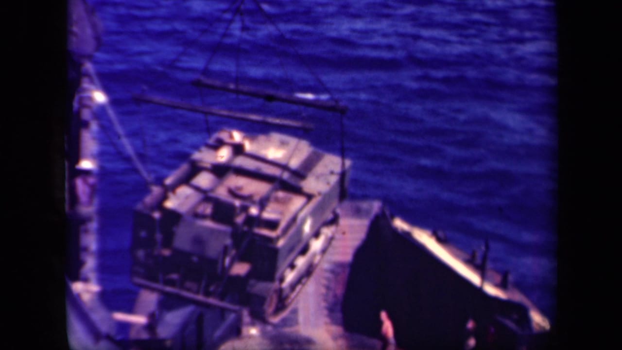 Crane rigging lowers a large load toward the ship deck in wartime Leyte Gulf footage.