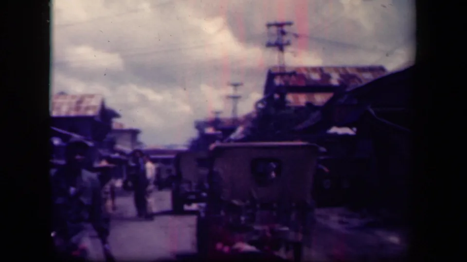 Leyte Gulf street view showing a foreground vehicle or cart, men in the road, roadside structures, utility poles, and cloudy sky.