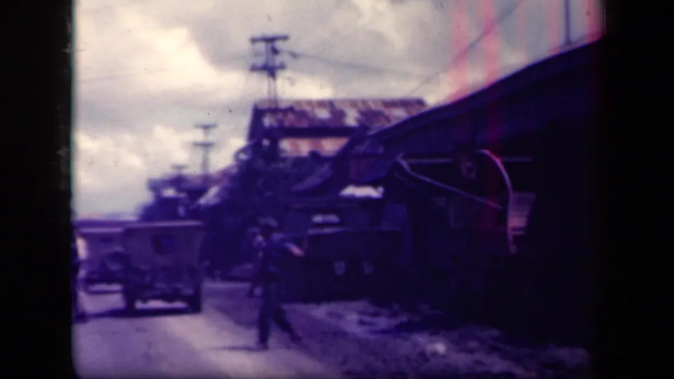 A car and a pedestrian appear on a dirt road in Leyte Gulf, Philippines, with utility poles and roadside buildings visible.