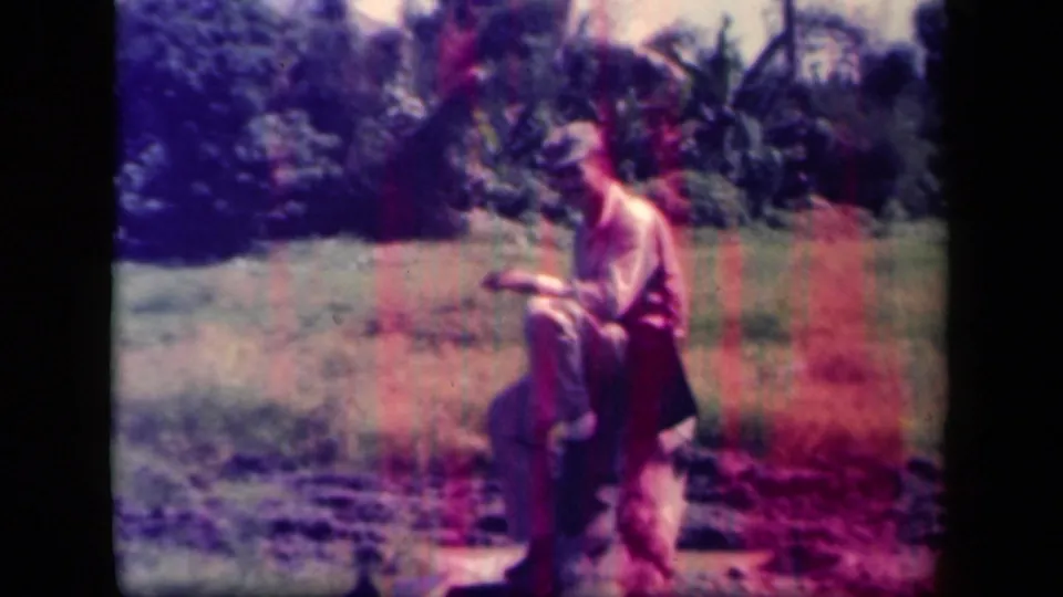 In metadata-supported 1944 Leyte Gulf footage, a uniformed soldier sits on a log in a green tropical field.