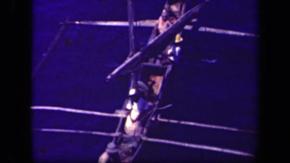 A narrow outrigger canoe carrying several men is viewed from above or nearby in the 1944 Leyte Gulf home-movie footage.