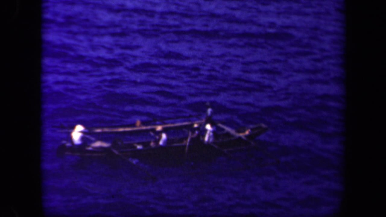 A distant outrigger canoe carries several people across Leyte Gulf, with paddles or spars extending over the water.