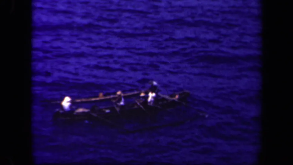 A traditional outrigger canoe remains in view on Leyte Gulf, its passengers and side supports silhouetted against the blue sea.
