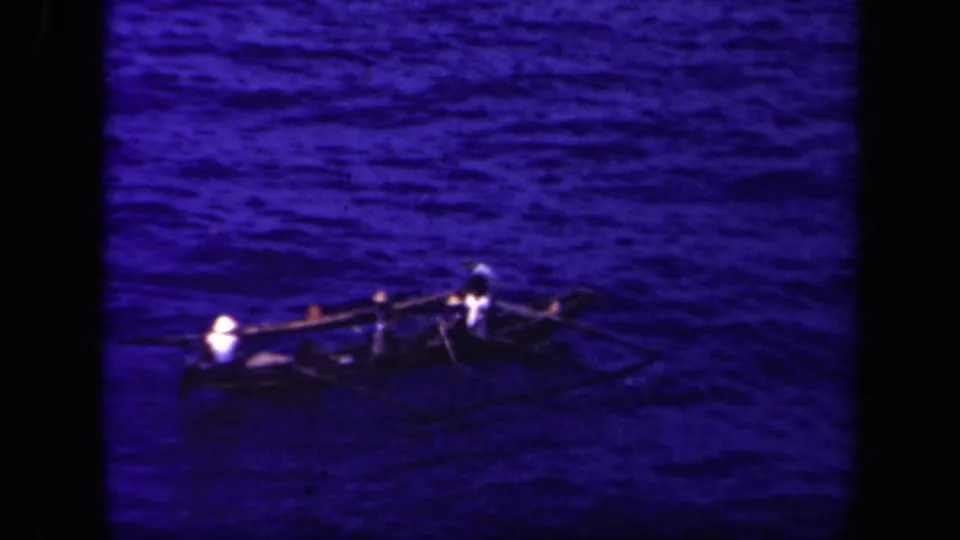 A small outrigger canoe with several occupants moves across blue water in Leyte Gulf, Philippines, in 1944 home-movie footage.