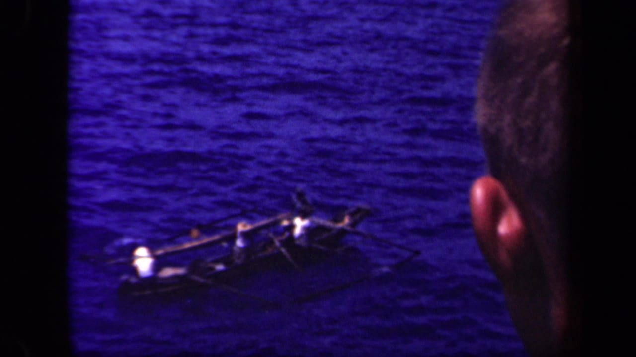 Outrigger canoe on blue water with a partial head at the right edge.