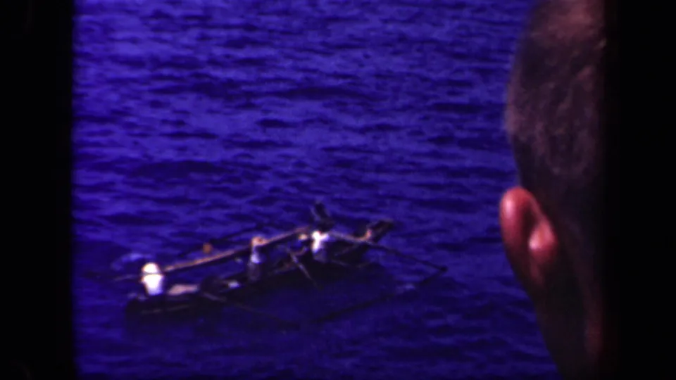 The canoe continues across Leyte Gulf water while a partial observer's head appears along the right edge of the frame.