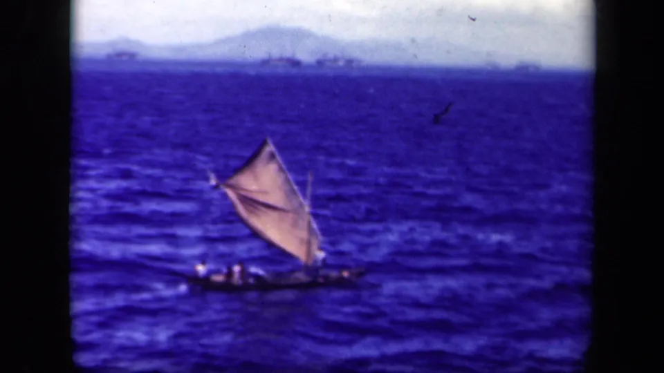 Distant 1944 Leyte Gulf frame showing a small handmade sailboat with figures aboard and a triangular sail against open water.