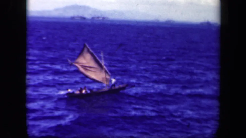 Distant 8mm frame of a small sailboat in Leyte Gulf, with several figures low in the boat and hazy land on the horizon.
