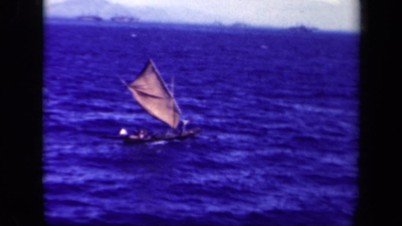 Triangular-sailed boat riding low in rough blue sea.