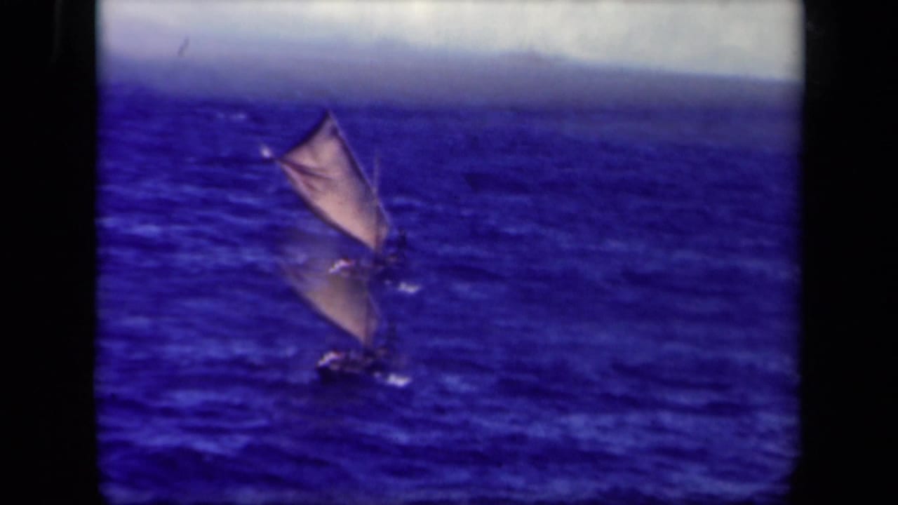 1944 Leyte Gulf 8mm frame showing a small sailboat with raised canvas sails crossing choppy blue water.