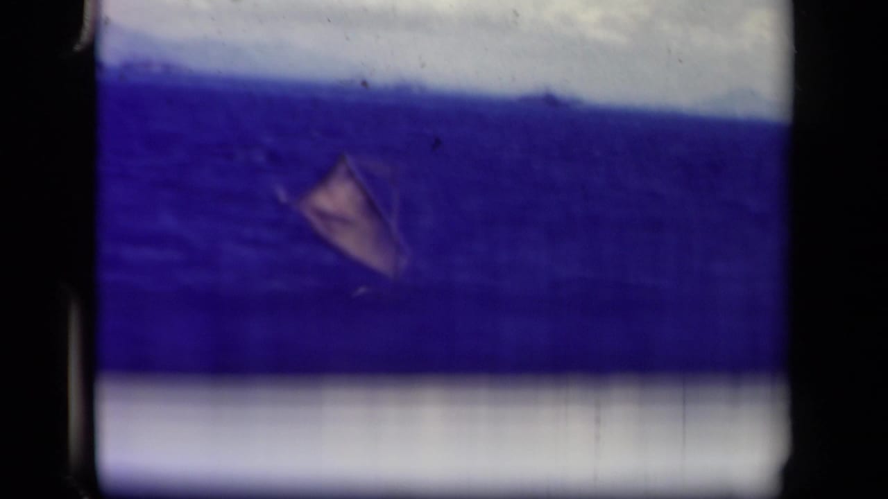 Distant sailboat appears against dark blue Leyte Gulf water in a faded 1944 8mm frame.