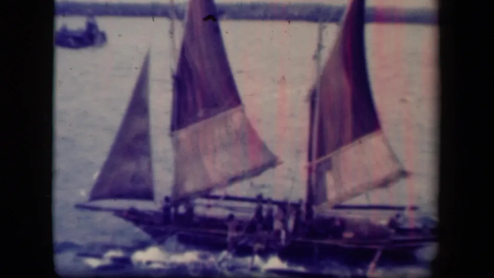 1944 Leyte Gulf frame showing an open sailboat with people aboard, canvas sails, and choppy water at the hull.