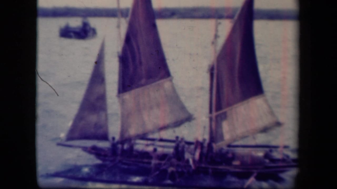 1944 Leyte Gulf footage shows traditional sailboats with large triangular sails crossing open water, with crew figures visible aboard.