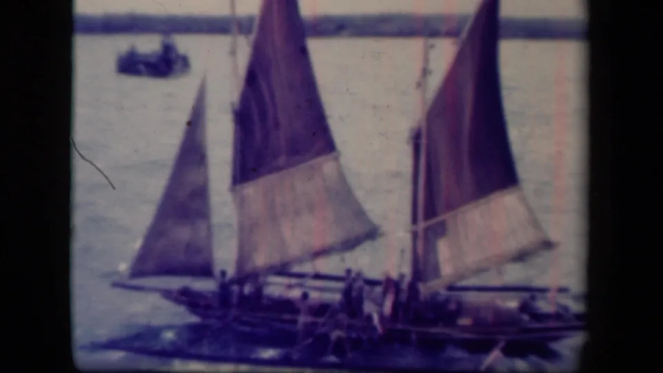 1944 Leyte Gulf footage shows traditional sailboats with large triangular sails crossing open water, with crew figures visible aboard.