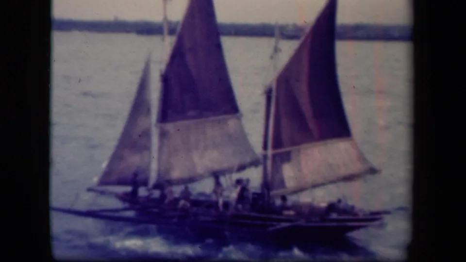 Leyte Gulf home-movie frame showing sailboats with tall cloth sails and visible crew moving over choppy water.