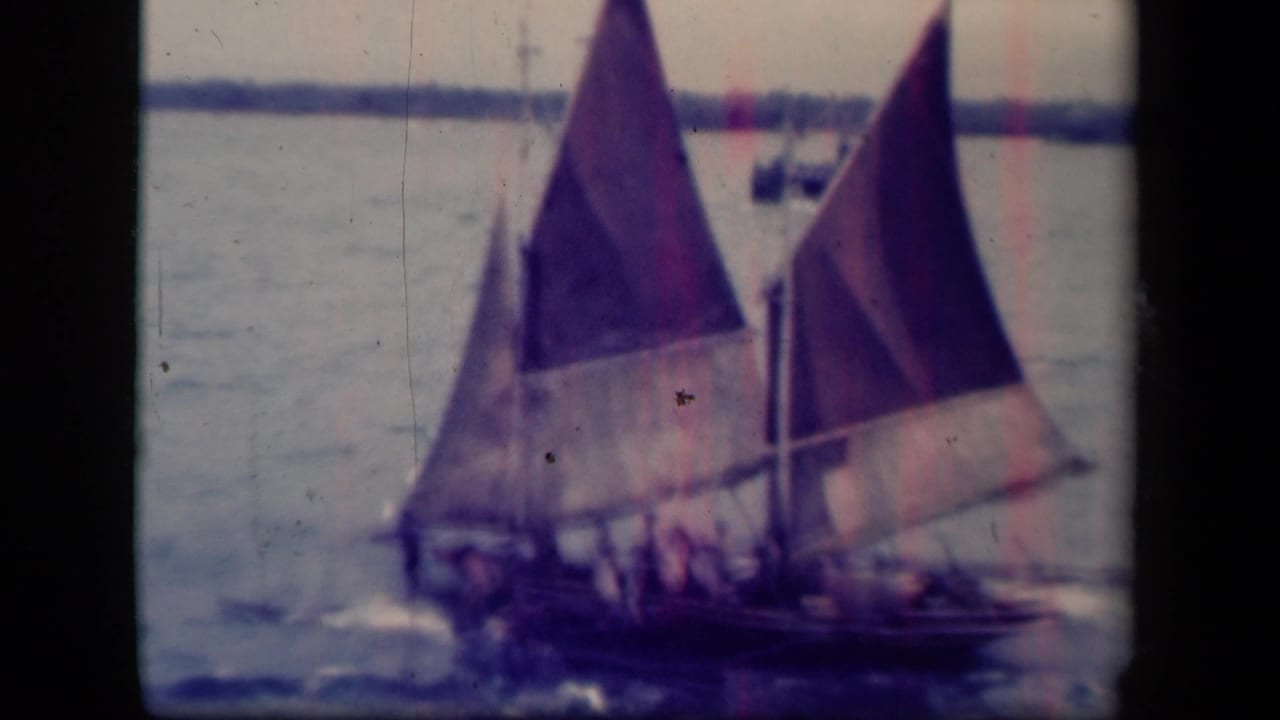 1944 Leyte Gulf footage shows a traditional sailboat with colorful triangular sails and passengers moving across calm water.