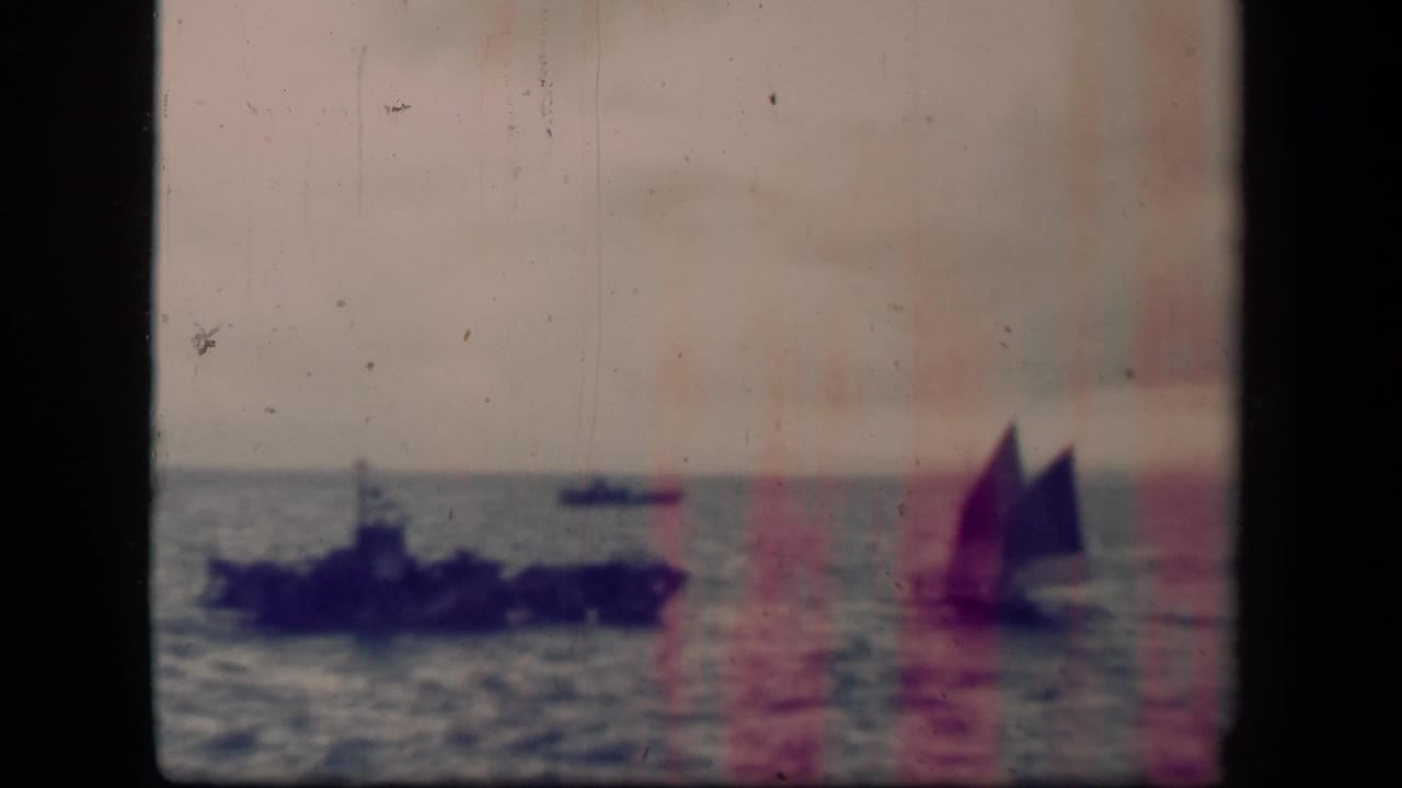 Leyte Gulf 1944 frame with a dark naval vessel left of center, a distant boat on the horizon, and a sailboat to the right.