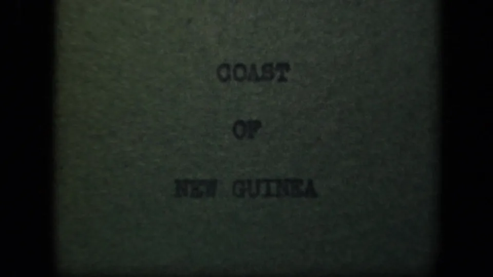 Title card reading "COAST OF NEW GUINEA" on a green-tinted 8mm frame with soft focus and visible film grain.